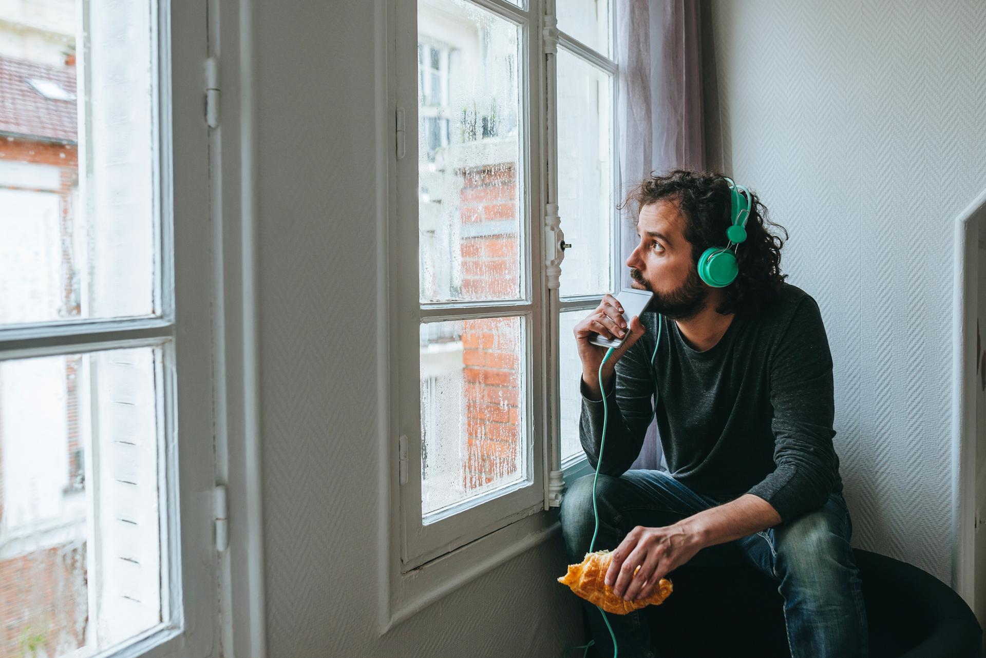 Man listening music with headphones and smartphone at home